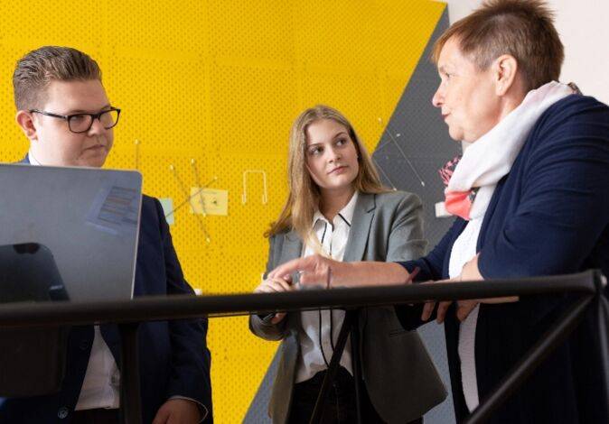 Ausbilderin Meike Fischer mit den dual Studierenden Lena Arendt und Niklas Schneider im Gespräch.